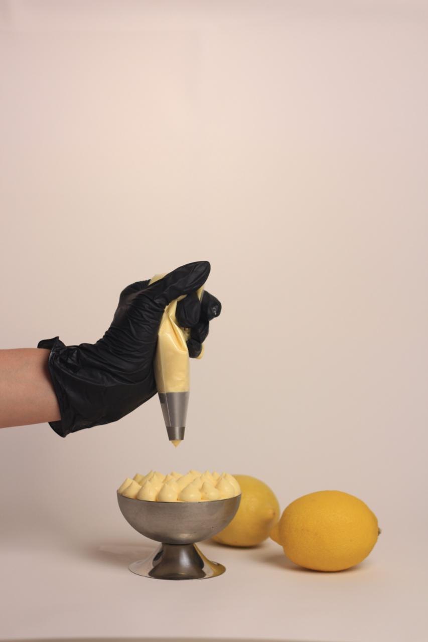Cream being piped into a coupe dessert beside fresh lemons