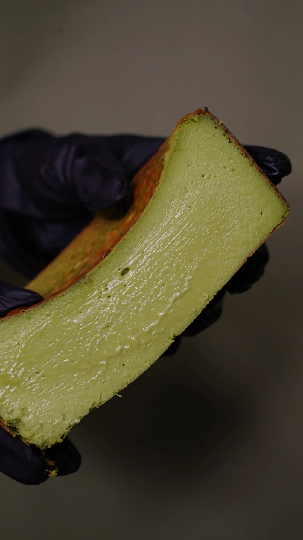 A green cheesecake slice held up to reveal its texture
